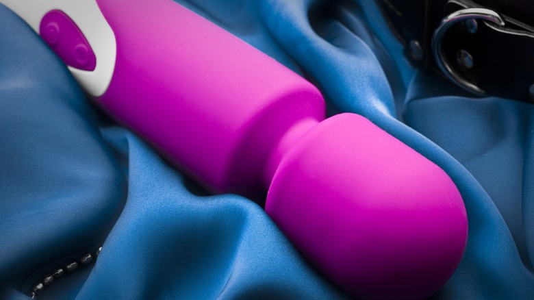 Vibrator cu bagheta roz pe cearsaf de matase albastra